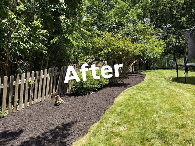 Fence-line planting bed with fresh mulch and a clean curved lawn edge